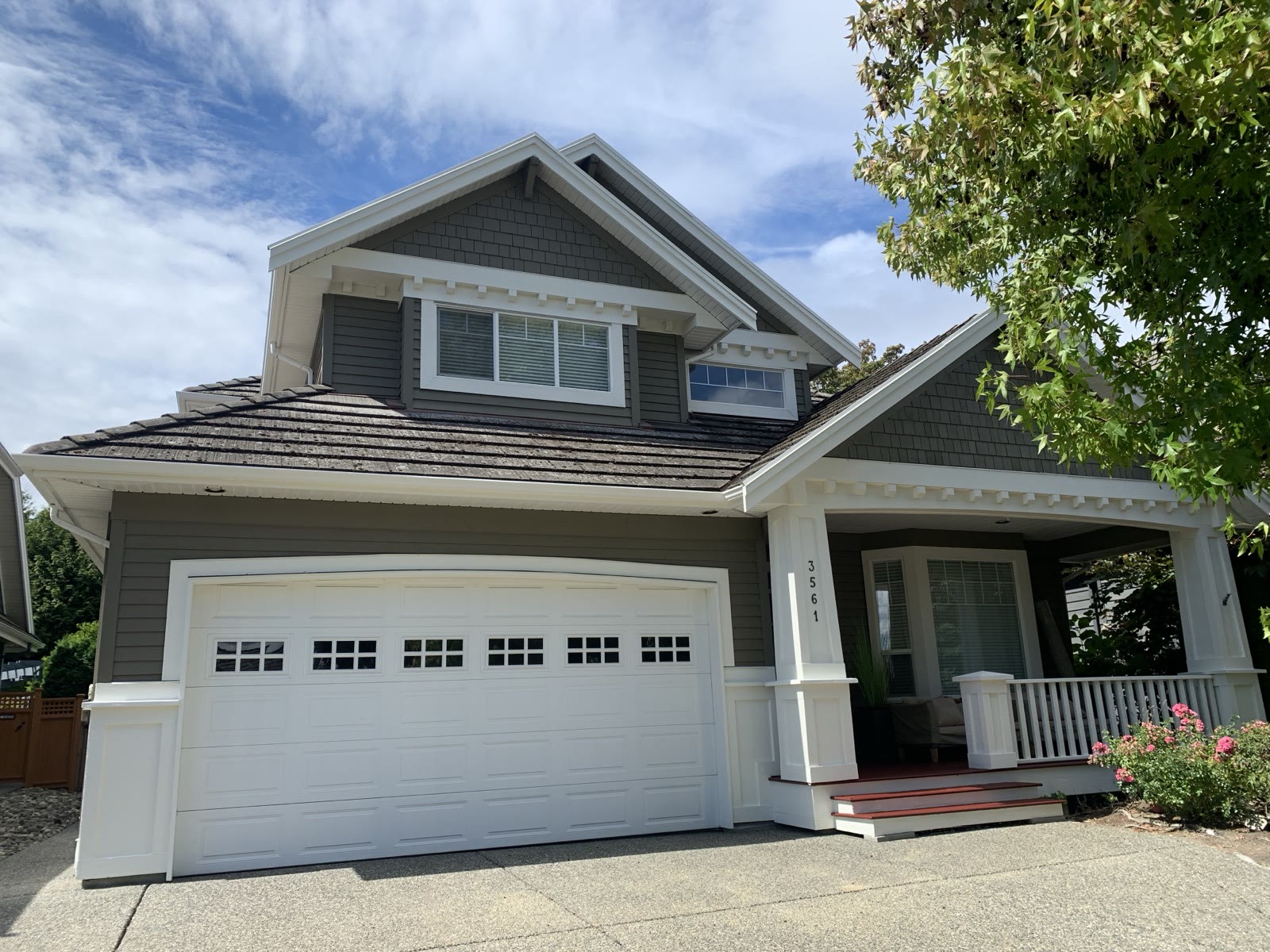 The same craftsman house finished — deep warm grey siding, crisp white trim, freshly stained red porch steps